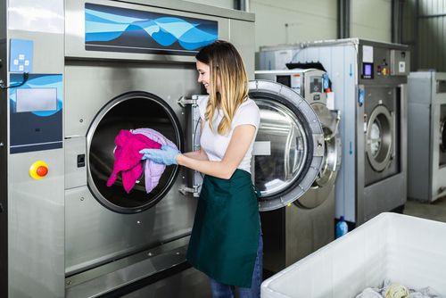 woman loading commercial washing machine