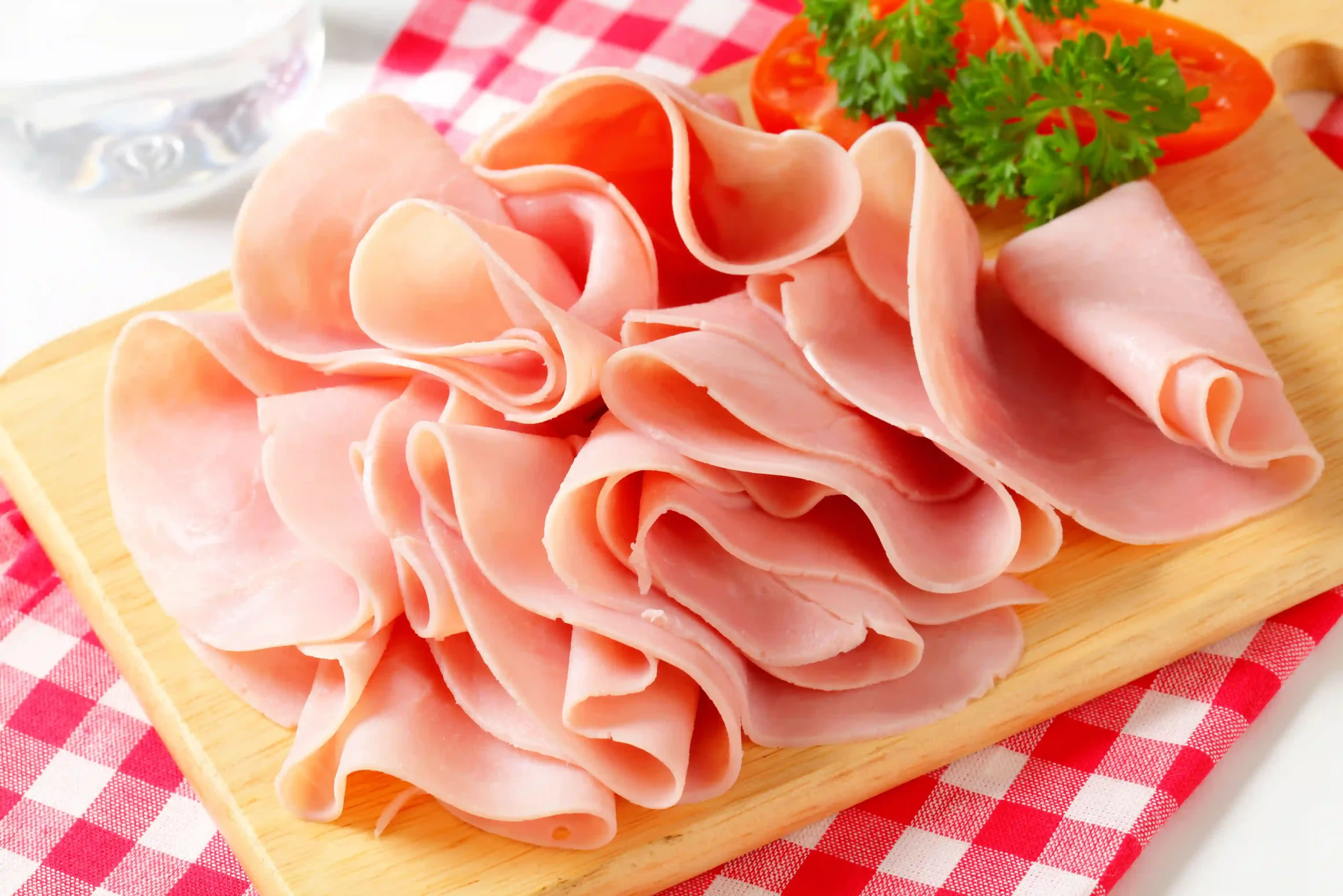 Sliced ham on red and white checked tablecloth