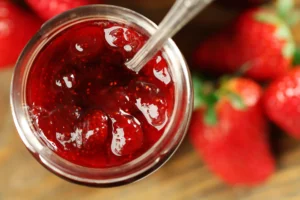 open jar of jam next to strawberries